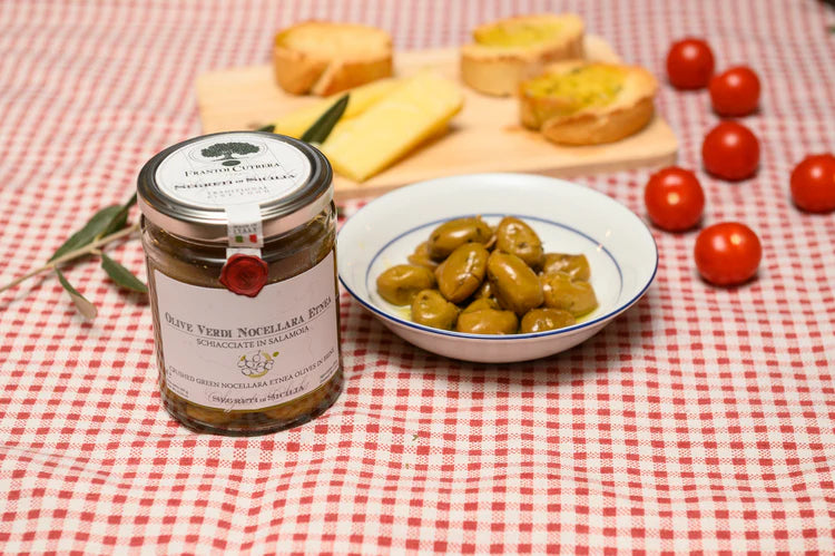 Jar of olive spread with a plate of olives on a red checkered tablecloth.